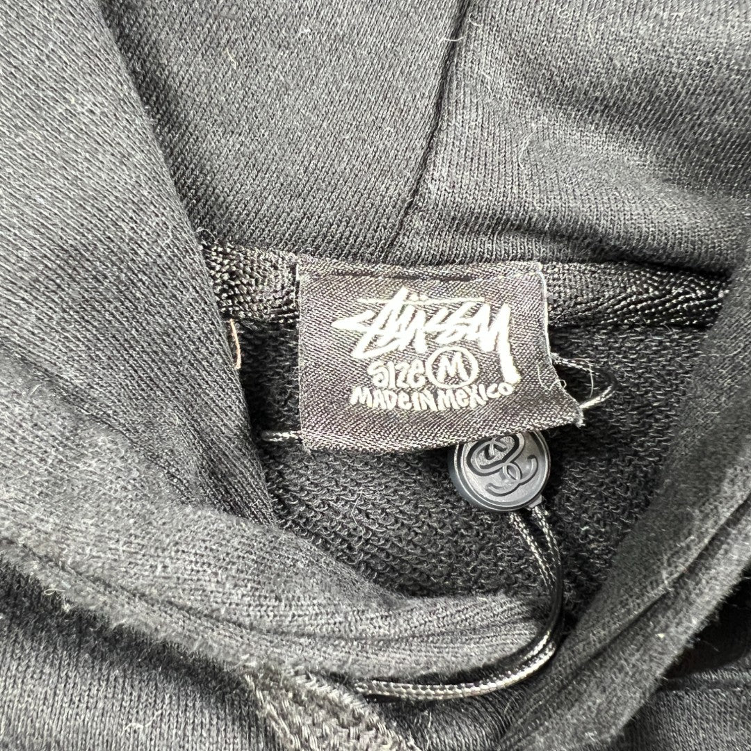 Hoodie stussy basic noir avec le logo stussy vue de l'étiquette