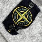 pull stone island gris avec le badge stone island sur la manche gauche vue du badge